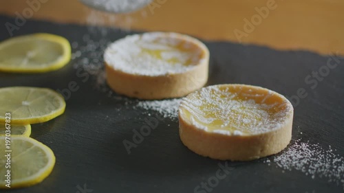 Wallpaper Mural Baker sifts powdered sugar over lemon tarts on a black slate, garnished with fresh lemon slices. Torontodigital.ca