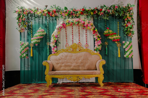 Wallpaper Mural Elegant golden sofa with plush upholstery on a red ornate carpet, set against a teal backdrop adorned with fresh flower garlands and decorative elements, ready for a special event Torontodigital.ca