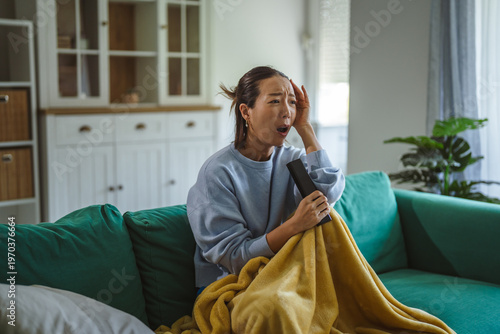 Woman feeling shocked and scared watching upsetting news on tv