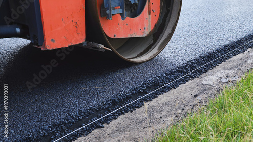 Steamroller compacting fresh asphalt during road construction and infrastructure work