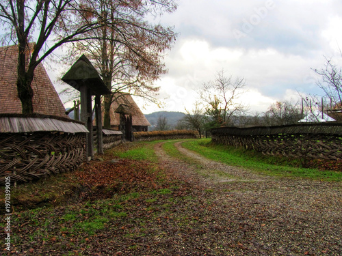 Rustic traditional woven wattle fences along a rural village road in autumn