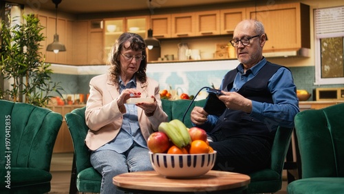 Tableau sur toile Two retirees, daily prescribed pills, monitoring blood pressure, BP monitor, old couple doing in-home medical routine with treatment and vital signs measurements for prevention