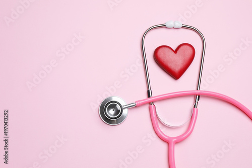 Fotografía Stethoscope and heart figure on pink background, flat lay