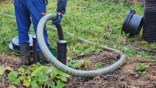 Bilde på lerret Worker performing septic tank maintenance, pumping waste using a large hose