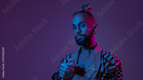 Neon light studio close-up portrait handsome black gay man looking camera. Seductive sexy man wear make up, transgender person in ultraviolet light. Nightclub and nightlife concept