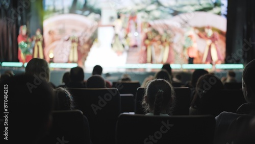 People watching a live stage performance in a darkly lit theater auditorium