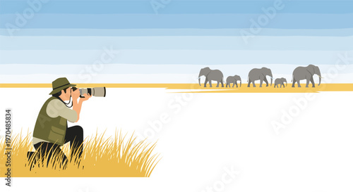 A professional wildlife photographer wearing a green vest and hat kneels in golden grass to capture images of a distant elephant herd under a blue sky.