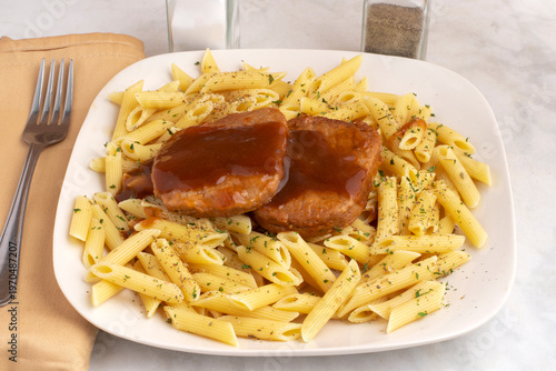 фотографія penne pasta  top with salisbury steak  and gravy