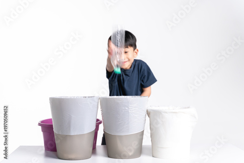 A young boy drops a plastic bottle into the correct trash bin, promoting recycling and environmental responsibility.
