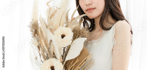 A stylish woman holding a dried flower swag.