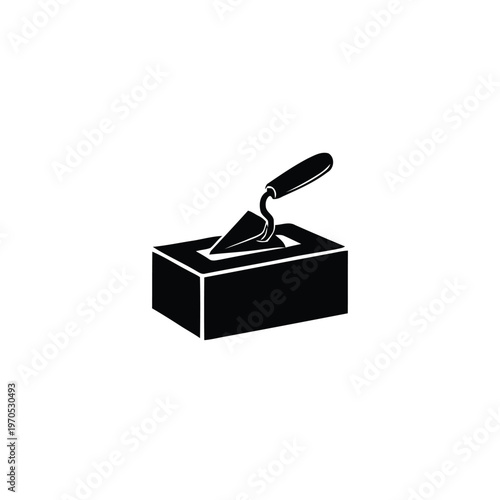 A trowel rests on a rectangular concrete block in an industrial setting.