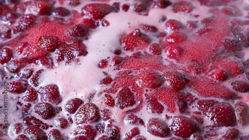 Fresh strawberries immersed in bubbling liquid, creating a delicious aroma. Indoor kitchen scene radiates warmth and homey vibes, perfect for cooking.