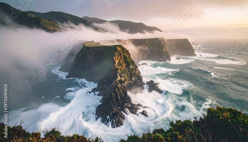 Rugged cliffs jut from ocean; waves crash as mist shrouds mountains