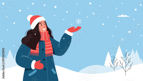 Happy young woman wearing winter clothing and knitted hat catching falling snowflakes in a snowy outdoor landscape.