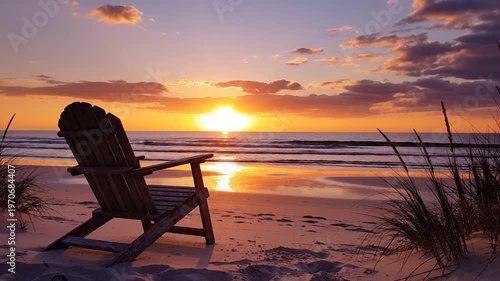 A solitary wooden chair awaits on a sandy beach as the sun sets over the tranquil ocean, casting a warm glow
