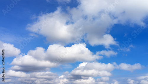 A beautiful celestial landscape with cumulus clouds in a sunny blue sky. Light overcast against a backdrop of pleasant summer weather. The natural background is in various shades of blue