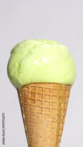 4K Vertical video Time-lapse Lime ice cream scoop in waffle cone isolated on clean background Fresh green dessert with smooth creamy texture, ideal for summer refreshment food concept.