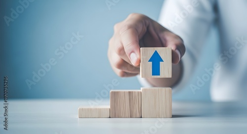 Building success hand placing block with upward arrow on wooden stack