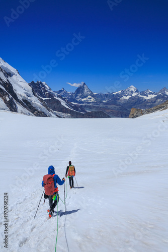 Mountaineers in rope team with crampons descending on glacier Grenzgletscher and mountain panorama with summits Matterhorn and Dent Blanche (left to right) in Pennine Alps, Switzerland