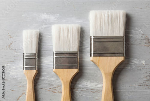 Three clean new paintbrushes of different sizes on a painted surface