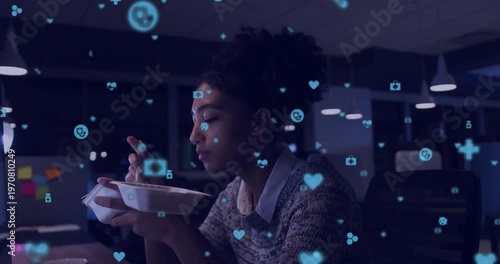 Vertical video: Woman eating at desk working late, watching screen, floating health icons over her