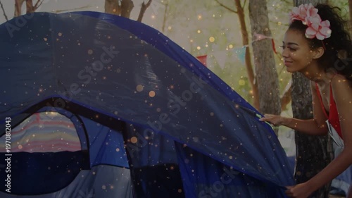 Woman approaching tent, pulling flysheet to secure dome for camping, particles highlighting zipper