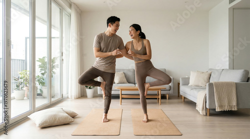 Young Asian Couple Practicing Yoga Together at Home, Fun and Balanced Lifestyle in Modern Living Room