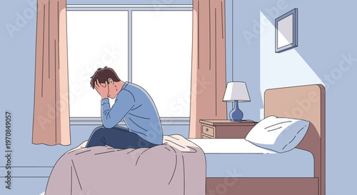 Man sitting on the edge of his bed in the morning feeling stressed and tired with his head in his hands after waking up.