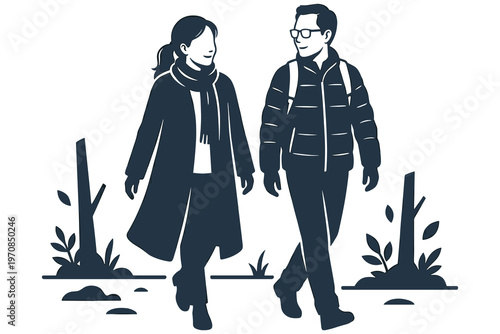 A man and woman walking together outdoors in winter weather with plants on ground.