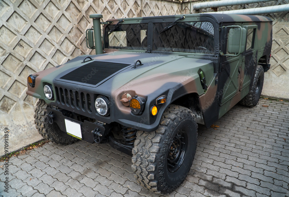 Fototapeta premium Military Humvee parked on an street, showcasing its rugged design and operational readiness in a secure military base. Khaki camouflage military Hummer front view. HMMWV.