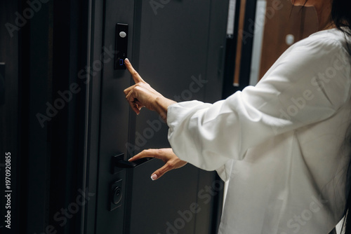 Photos Woman in white blouse pressing doorbell button on modern black door with sleek d
