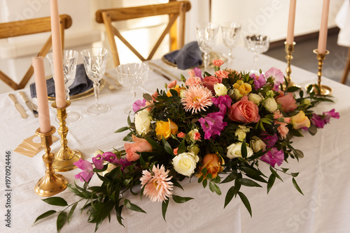 Photos Elegant floral centerpiece with pink roses, yellow dahlias, and purple sweet peas on a white linen tablecloth