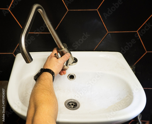 Plumber changes broken, leaking plumbing fixtures in the bathroom. Plumber uses a wrench to install the faucet in the bathroom. 