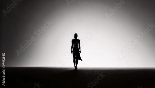 Silhouette of a person walking alone in a vast empty space.