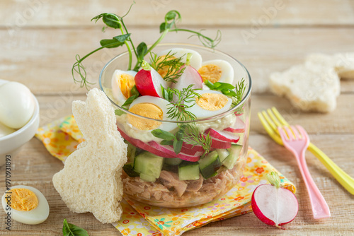 Salad with tuna, eggs, cucumber and raddish in glass