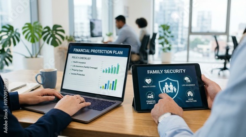 Professional financial advisor and client reviewing insurance policy and family protection plan on laptop and tablet in modern office for long term security and wealth management strategies.