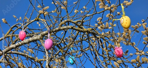 colorful eggs hang from palm branches.