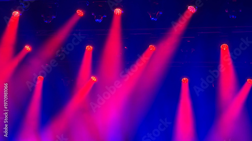 red and pink light beams on blue stage during music concert