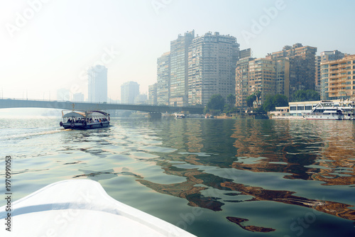 Beautiful skyline of Cairo reflected in the Nile with boats cruising along the calm waters in the early morning mist