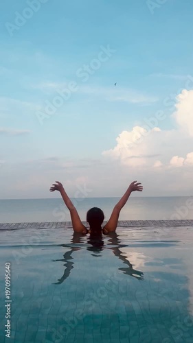 Back side view of young Asian woman enjoy sea n sky swiming n doing yoga in oceanside pools, calm ocean wave n sea water on clear blue sky n fluffy white cloud background, Outdoor lifestyle concept