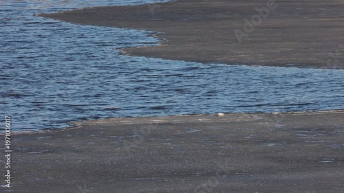 Melting grey ice floe floating on dark blue river water