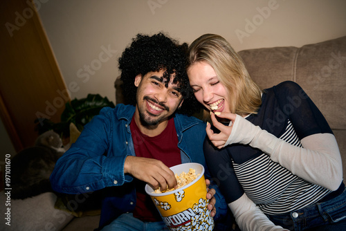 Happy diverse couple enjoying movie night with popcorn