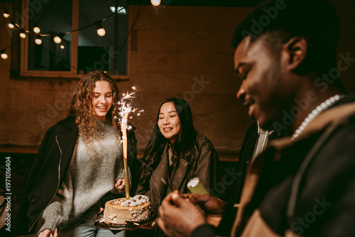 Tablou pe pânză Friends celebrating a birthday indoors with a cake and sparklers in a cozy, fest