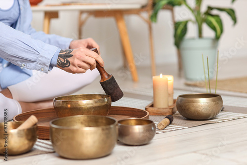 Obraz na płótnie Young woman using Tibetan singing bowls on floor at home, closeup