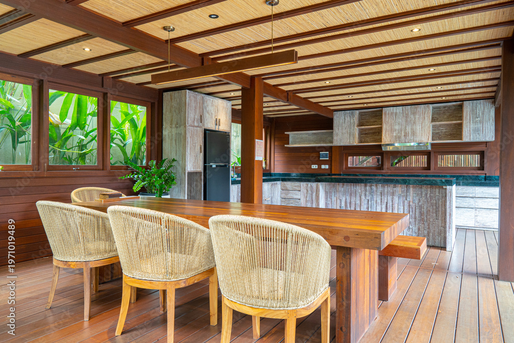Fototapeta premium A large open kitchen with a wooden dining table and chairs. The chairs are white and the table is made of wood. The kitchen is well-lit and has a warm, inviting atmosphere