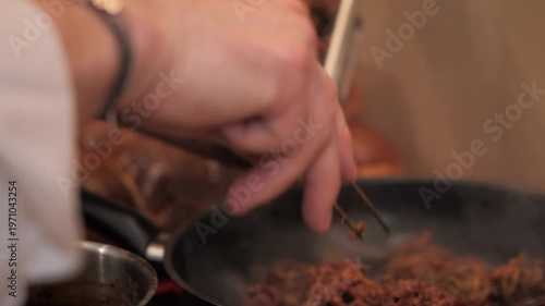 Chef’s hands placing meat in frying pan