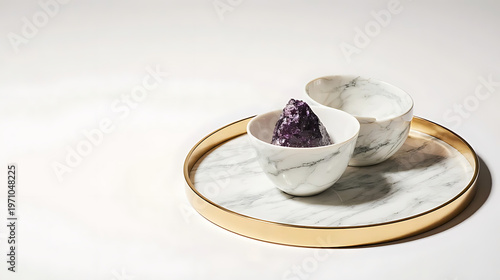A white marble tray with gold trim holds two decorative bowls, one containing a sparkling purple stone isolated