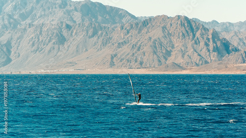 Fotografie People enjoying water sports like windsurfing and kitesurfing on a sunny sea bea