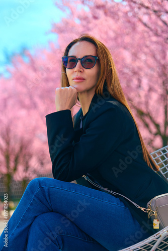 girl walks through a park with flowering trees