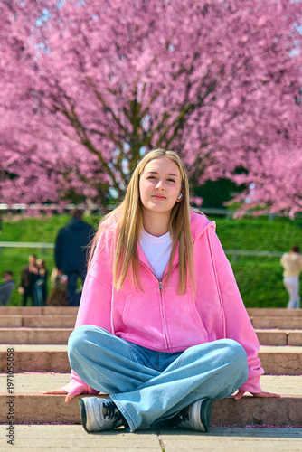 A girl walks through a park with flowering trees